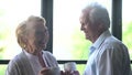 Senior couple standing near window and having coffee in living room Royalty Free Stock Photo