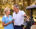 Senior Couple Standing Next To Buggy On Golf Course Marking Score Card Together Royalty Free Stock Photo