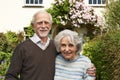 Senior Couple Standing Outside Pretty Cottage