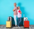 Senior couple with suitcases near color wall