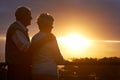 Senior couple, sunset and relax on balcony in outdoor, bonding and love on vacation or holiday. Retirement, elderly