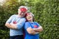 Senior couple in Superhero costume lauging with arms crossed