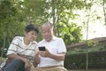 Senior couple surfing and reading phone together in the park Royalty Free Stock Photo