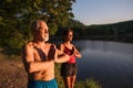 Senior couple in swimsuit standing by lake outdoors doing yoga. Royalty Free Stock Photo