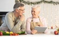 Senior Couple With Tablet Computer Preparing Christmas Dinner In Kitchen Royalty Free Stock Photo