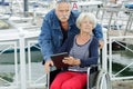 senior couple with tablet by harbour woman in wheelchair Royalty Free Stock Photo