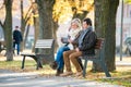 Senior couple with tablet sitting on bench. Autumn park. Royalty Free Stock Photo