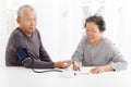 Senior couple taking blood pressure in living room Royalty Free Stock Photo