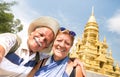 Senior couple taking selfie at golden temple in Ko Samui - Happy retired people traveling to Thailand wonders - Active elderly