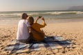 Senior couple taking selfie with mobile phone relaxing on picnic blanket at beach Royalty Free Stock Photo