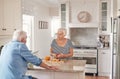 Senior couple talking together while preparing breakfast in their kitchen Royalty Free Stock Photo