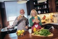 Couple talking together while standing at their kitchen counter preparing a healthy breakfast of fruit Royalty Free Stock Photo