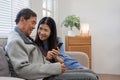 A senior couple in their 60s spends their free time relaxing and having fun together on the sofa in the living room. Royalty Free Stock Photo