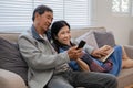 A senior couple in their 60s spends their free time relaxing and having fun together on the sofa in the living room. Royalty Free Stock Photo