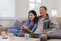 A senior couple in their 60s spends their free time relaxing and having fun together on the sofa in the living room. Royalty Free Stock Photo