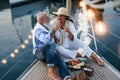Senior couple toasting champagne and eating fruits on sailboat vacation - Happy elderly people having fun celebrating wedding Royalty Free Stock Photo