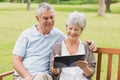 Senior couple using digital tablet on bench at park Royalty Free Stock Photo