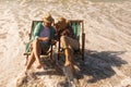 Senior couple using mobile phone while relaxing on sun lounger at beach Royalty Free Stock Photo