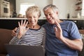 Senior couple video calling on a laptop waving at screen Royalty Free Stock Photo