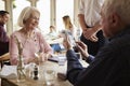 Senior Couple With Waiter Paying Bill In Restaurant