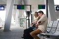 Senior couple waiting on train station, looking at watch.