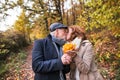 Senior couple on a walk in a forest in an autumn nature, holding leaves and kissing. Royalty Free Stock Photo