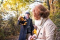 Senior couple on a walk in a forest in an autumn nature, holding leaves. Royalty Free Stock Photo