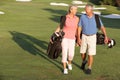 Senior Couple Walking Along Golf Course Royalty Free Stock Photo