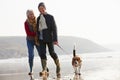 Senior Couple Walking Along Winter Beach With Pet Dog Royalty Free Stock Photo