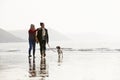 Senior Couple Walking Along Winter Beach With Pet Dog Royalty Free Stock Photo