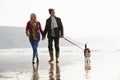 Senior Couple Walking Along Winter Beach With Pet Dog Royalty Free Stock Photo