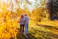 Senior couple walking in autumn forest. Middle-aged man and woman hugging and chilling outdoors