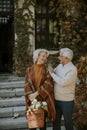 Senior couple walking with basket full of flowers and groceries in autumn park Royalty Free Stock Photo