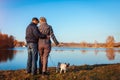 Senior couple walking pug dog in autumn park by river. Happy man and woman enjoying time with pet Royalty Free Stock Photo