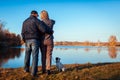 Senior couple walking pug dog in autumn park by river. Happy man and woman enjoying time with pet. Royalty Free Stock Photo