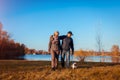 Senior couple walking pug dog in autumn park by river. Happy man and woman enjoying time with pet Royalty Free Stock Photo