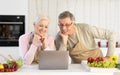 Senior Couple Watching Online Cooking Course On Laptop In Kitchen Royalty Free Stock Photo