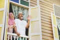 Senior couple waving from house window