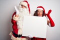 Senior couple wearing Santa Claus costume holding banner over isolated white background very happy and excited, winner expression Royalty Free Stock Photo