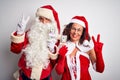 Senior couple wearing Santa Claus costume holding dollars over isolated white background smiling looking to the camera showing Royalty Free Stock Photo