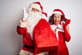 Senior couple wearing Santa Claus costume holding sack over isolated white background very happy and excited, winner expression Royalty Free Stock Photo