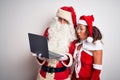 Senior couple wearing Santa Claus costume using laptop over isolated white background scared in shock with a surprise face, afraid Royalty Free Stock Photo