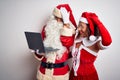 Senior couple wearing Santa Claus costume using laptop over isolated white background stressed with hand on head, shocked with