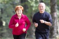 Senior couple wearing sportswear and running in forest Royalty Free Stock Photo