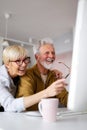 Senior couple websurfing on internet with laptop at home