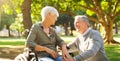 Senior couple, wheelchair and happy outdoor at a park while talking with love, care and respect. A elderly man and woman