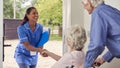 Senior Couple With Woman In Wheelchair Greeting Nurse Or Care Worker Making Home Visit At Door Royalty Free Stock Photo