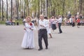 Senior couples dance in park.