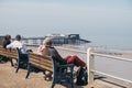 Senior couples enjoying sunny day on a bench by the sea in Cromer, Norfolk, UK