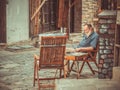 Senior craftsman resting at a table on Samovodska Charshiya street one of the most important tourist attraction in Veliko Tarnovo